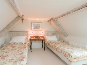 two twin beds in a room with a table at Sweet Pea Cottage in Kingston