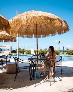 a woman sitting at a table under a straw umbrella at Punta Borinquen Resort in Aguadilla