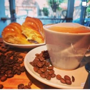 a cup of coffee and a plate of coffee beans at Apart hotel Magda in Venado Tuerto
