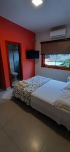 a bedroom with a bed and a red wall at Pousada Hymbe in Trindade