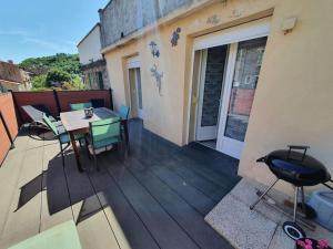 uma varanda com uma mesa e cadeiras num edifício em Well equipped apartment, large terrace, BBQ & WIFI em Ria