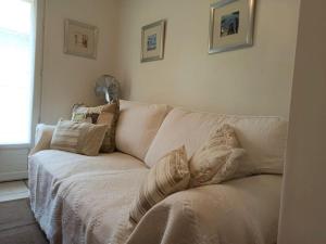um sofá branco numa sala de estar com almofadas em Well equipped apartment, large terrace, BBQ & WIFI em Ria