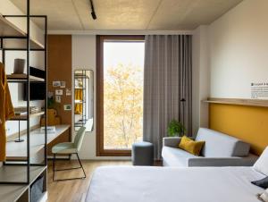 - une chambre avec un lit, un canapé et une fenêtre dans l'établissement Kora Green City - Aparthotel Passivhaus, à Vitoria-Gasteiz