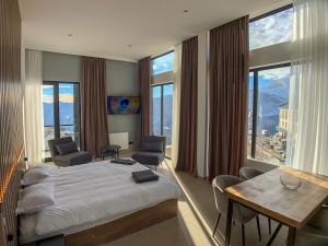 a bedroom with a bed and a desk and windows at New Gudauri View in Gudauri