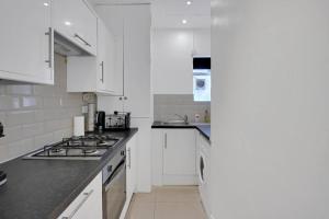 a kitchen with white cabinets and a stove top oven at Hamilton Apartments hosted by Maysa London in London