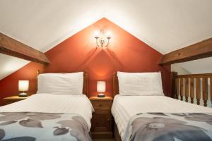 two beds in a room with red walls at The Mountain Cottages - Carpenters in Coniston