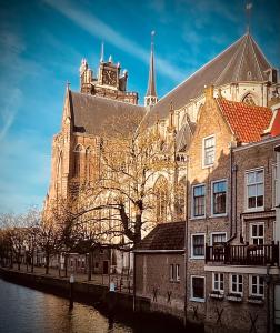 un grande edificio con torre dell'orologio accanto a un fiume di Arthouse Dordrecht a Dordrecht