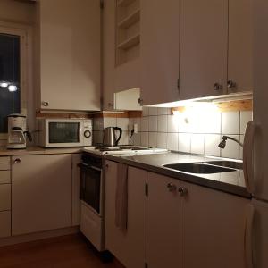 a kitchen with white cabinets and a sink and a microwave at Tilava kolmio keskustassa in Ylivieska