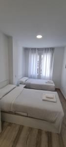 3 camas en una habitación con paredes blancas y suelo de madera en APTO TANEZ SAN FRANCISCO STYLE, a en Madrid