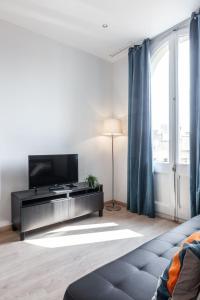 uma sala de estar com uma televisão e um sofá em Bright Apartment with Balconies em Barcelona