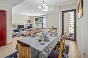 a dining room with a table and chairs and a living room at Lovely 2-bed condo in JBR - 5 mins from beach - Palm View! in Dubai