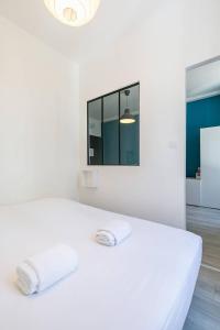 1 dormitorio blanco con 1 cama y 2 toallas en Le Bossuet en plein coeur du centre historique, en Dijon