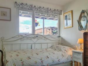 a bedroom with a white bed with a window at Whiteadder Cottage in Spittal