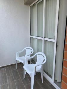 dos sillas blancas sentadas junto a una ventana en Apartamentos Amoblados, en Cali