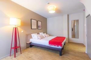 una camera con letto e lampada a pavimento rossa di Appart'City Confort Strasbourg Centre a Strasburgo