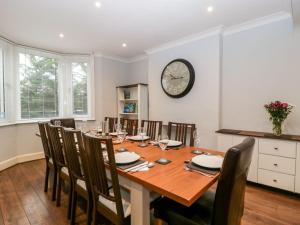 a dining room table with chairs and a clock on the wall at Tree of Life House, Number 27 Bere Lane in Glastonbury