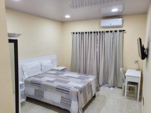 a bedroom with a bed and a tv and a desk at Apartahotel MACADANA in Nagua