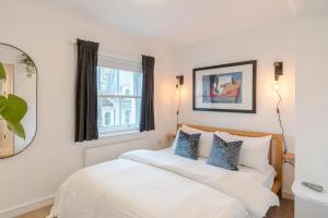 een slaapkamer met een wit bed met blauwe kussens bij Penthouse Kings Cross in Londen