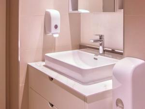 a bathroom with a white sink and a soap dispenser at Metropolitan Apartman - City View in Belgrade +8 photos