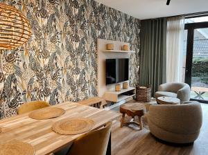 - une salle à manger avec une table, des chaises et une télévision dans l'établissement Hello Zeeland - Appartement Duno Lodge I, à Oostkapelle