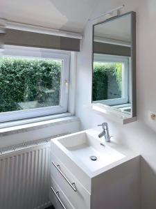 baño con lavabo y 2 ventanas en Vakantievilla 3 Beaufort, en Nieuwpoort