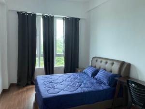 - une chambre avec un lit doté de draps bleus et une fenêtre dans l'établissement Homestay Sandakan CLL, à Sandakan