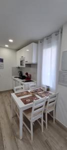 una cocina blanca con mesa y sillas. en APTO TANEZ LAS VEGAS STYLE, a, en Madrid
