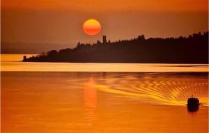 a sunset on the beach with the sun setting at Pet Friendly Stacaravan in Tuoro sul Trasimeno