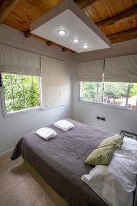a bedroom with a bed with two pillows and two windows at Mini Loft in Godoy Cruz