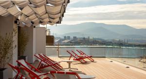 a deck with red chairs and a table on a balcony at Kora Green City - Aparthotel Passivhaus in Vitoria-Gasteiz
