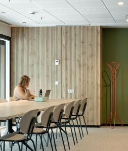 a woman sitting at a table in a conference room with a laptop at Kora Green City - Aparthotel Passivhaus in Vitoria-Gasteiz