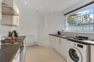 uma cozinha com uma máquina de lavar roupa e uma janela em Hamilton Apartments hosted by Maysa London em Londres