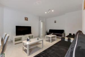 a living room with a couch and a flat screen tv at Hamilton Apartments hosted by Maysa London in London