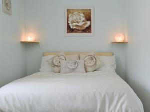 a bedroom with a white bed with two candles on it at The Butts Cottage in Stanhope