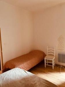 a bedroom with a bed and a white chair at Coquet studio coeur de ville au calme in Millau