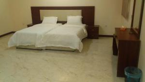 1 dormitorio con 2 camas con sábanas blancas y mesa en اغصان الريف لشقق المفروشة, en Riad
