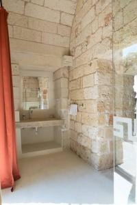 bagno con lavandino e parete in pietra di Old Villas Greco 1888 luxury swimming pool a Cutrofiano