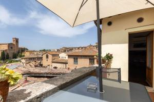 a view from the balcony of a house with an umbrella at Panoramic lovely time in Siena