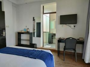 Dormitorio con cama, escritorio y TV en THE HOTEL EZRI en Meru