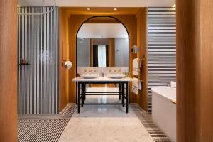 a bathroom with two sinks and a bath tub and a mirror at Hôtel Vernet Champs Elysées Paris in Paris