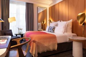 um quarto de hotel com uma cama, uma secretária e uma cadeira em Hôtel Vernet Champs Elysées Paris em Paris