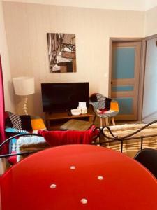 a living room with a red couch and a tv at Appartement Centre ville in Millau +3 photos