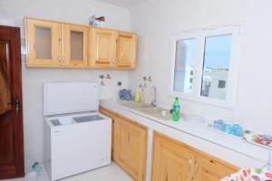 a kitchen with a white refrigerator and a sink at MBAO Sipres Appartement moderne bord de mer in Mbaw