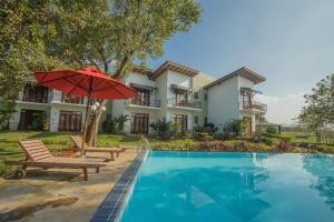 a house with a pool and a red umbrella at Sigiriya Wewa Addara Hotel - Hotel By The Lake in Sigiriya