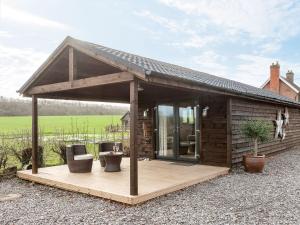 a small wooden cabin with a deck and chairs at Holders Cottage in Lassington