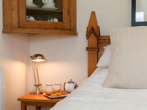a bedroom with a bed and a table with a lamp at Holders Cottage in Lassington
