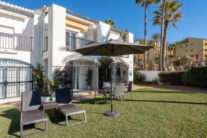 stół, krzesła i parasol przed domem w obiekcie Sea Front Beach House Macarena C w mieście Sitio de Calahonda