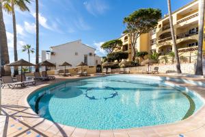 een groot zwembad met palmbomen en een gebouw bij On The Beach Sea View Patricia 132 in Marbella