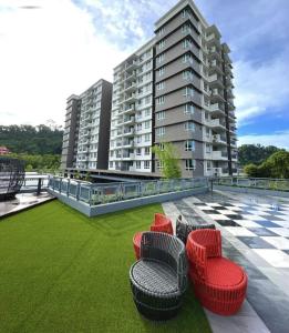 サンダカンにあるHomestay Sandakan CLLの芝生の上に赤い椅子が備わる大きなアパートメントです。