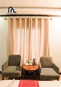 two chairs and a table in front of a curtain at Villa Pumalin in Luang Prabang